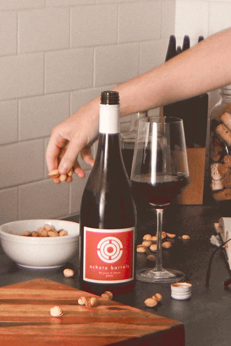 A bottle of wine on a counter-top, with a glass next to it.